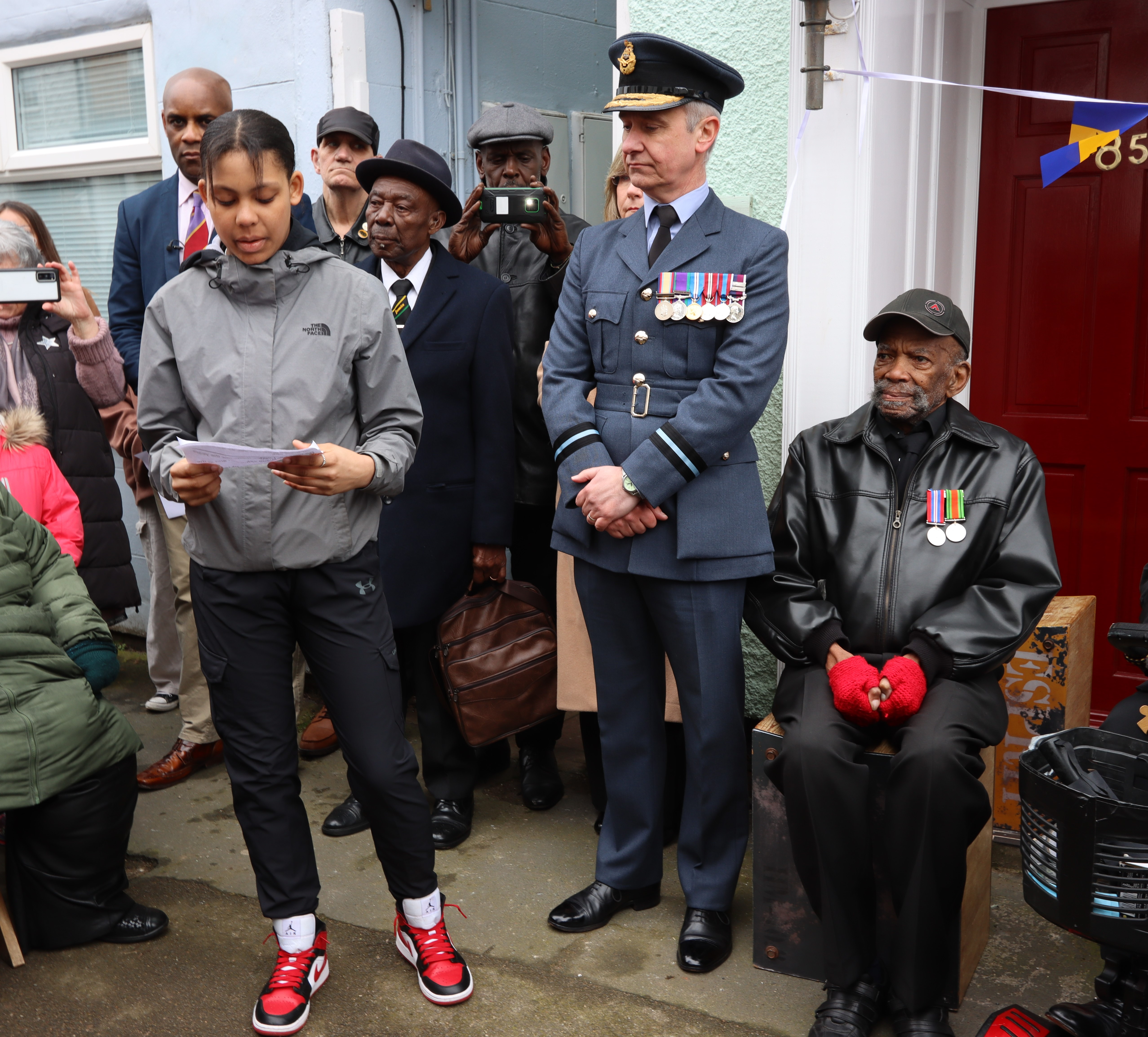 #Image shows RAF personnel standing with civilians and veterans.